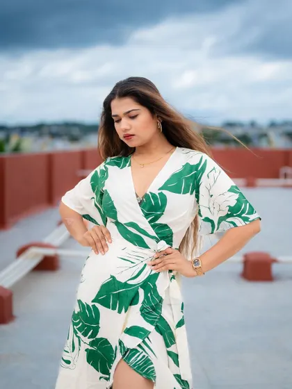 A rooftop portrait with a cloudy sky as the backdrop. The model's pose and the open environment create a dramatic and stylish fashion shot.