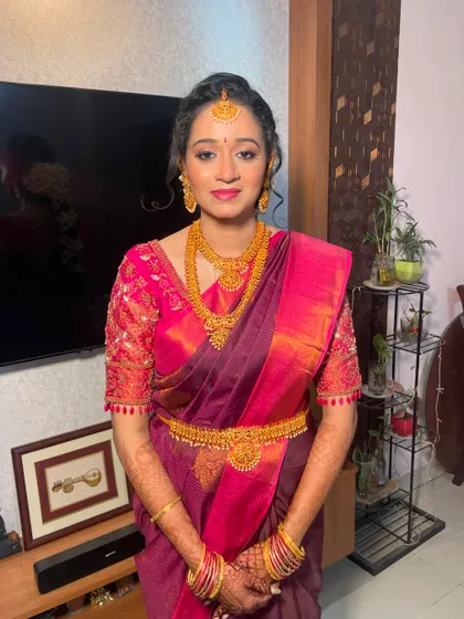 A full view of our Tamil bride's engagement look. The vibrant pink and purple saree is balanced with elegant gold jewelry and a radiant makeup finish.