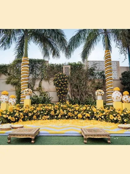 A classic Haldi setup with a yellow and white theme, featuring marigold decorations and traditional seating.