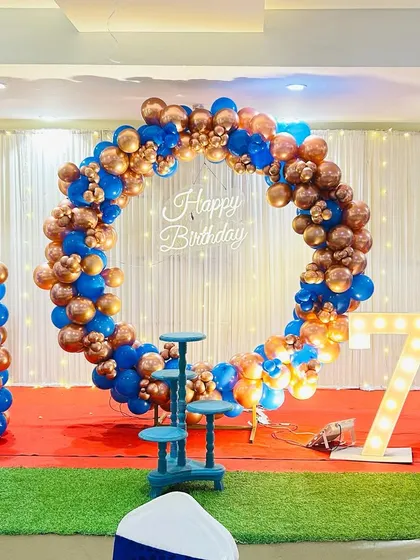 A 7th birthday party with a royal blue and bronze theme. The circular balloon arch and matching balloon columns create a sophisticated look.