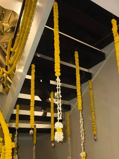 Simple and elegant Diwali decoration for a staircase, using hanging strings of marigold and other flowers.