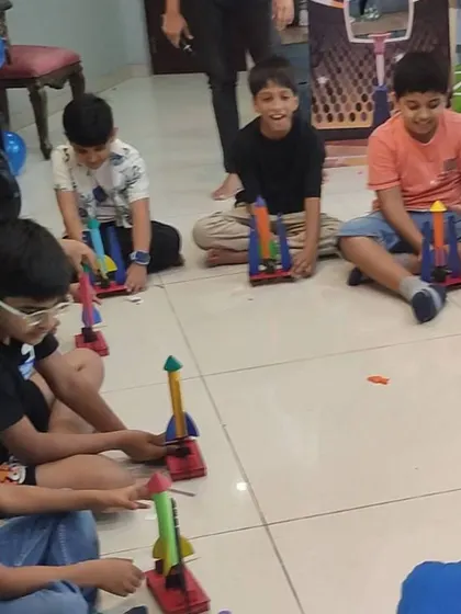 A group of boys eagerly prepares for a rocket launching competition, comparing designs and getting ready to see whose will fly the highest.