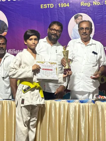 A proud student with his yellow belt, holding his trophy and certificate at the Shotokan Karate Institute event. Each competition is a valuable learning experience, building confidence and character.