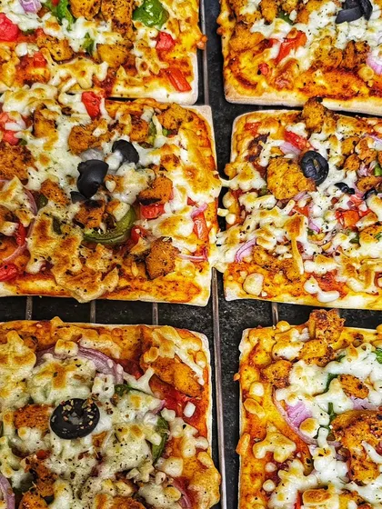 A close-up of the tandoori chicken pizza squares included in our birthday snack boxes. A cheesy and flavorful treat.