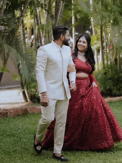 A happy couple in their engagement attire, taking a walk through a lush garden.