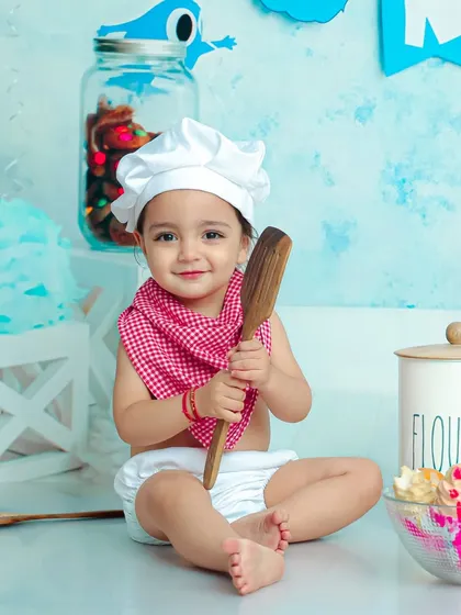 With a big wooden spoon and a charming smile, this future masterchef is ready to get cooking in our delightful kitchen setup.
