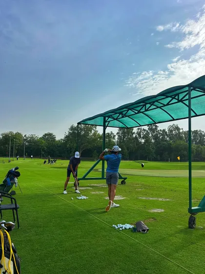 Two golfers practice side-by-side under the shade of our bay covers on a sunny day.