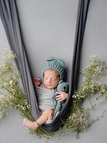 Gently cradled and surrounded by delicate baby's breath. This hanging prop pose is one of our favorites for creating an artistic and ethereal newborn photograph, highlighting how small and precious they are.