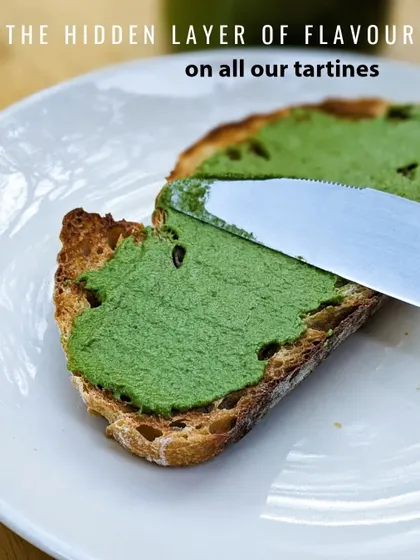 Revealing the secret to our tartines: a hidden layer of our house-made coriander pesto. It adds a fresh, herby kick to every bite.