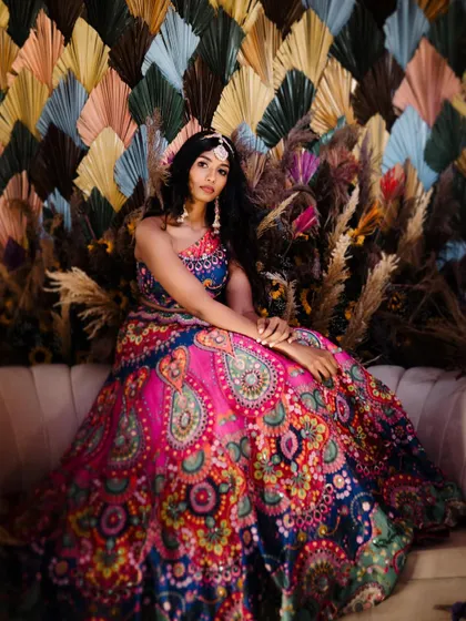 A stunning bridal portrait from a Mehendi ceremony, showcasing her colorful lehenga and the festive decor.