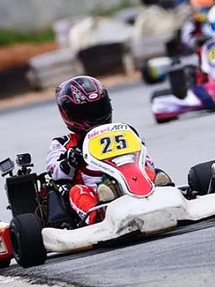 Our driver in kart number 25, navigating a tight corner with a rival in pursuit. We train our drivers for superior racecraft in wheel-to-wheel situations.