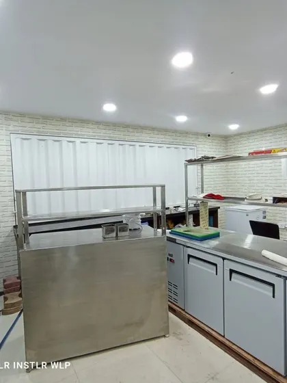 A wider view of the commercial kitchen with white brick wallpaper.