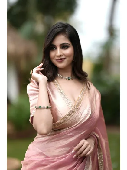 A close-up of the pink tissue silk saree, showing the delicate embroidery on the blouse and the shimmer of the fabric.