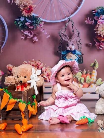 A close-up of a smiling baby in our bunny-themed set. Her joyful expression and the delightful props, like the teddy bear and carrots, make this an incredibly sweet photo.