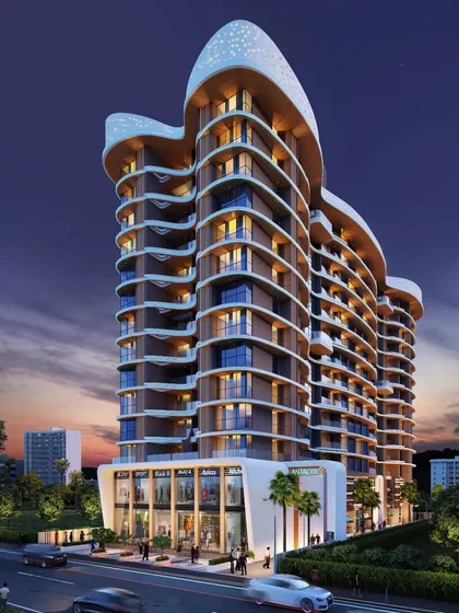 A night view of the Antalya residential project, showing the illuminated curved facade.