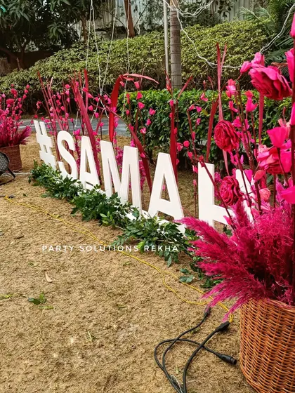 A bold wedding hashtag sign in hot pink. The custom sign is surrounded by matching floral arrangements, making it a vibrant and unmissable part of the decor.