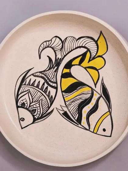 A full view of the sold fish plate with yellow accents. Each hand-painted plate adds a touch of charm and creativity to your space, telling its own unique story.