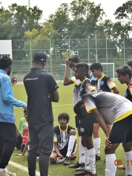 Coaches giving a pre-game talk to the U-15 team. Strategy and motivation are key before stepping onto the pitch for a league match.