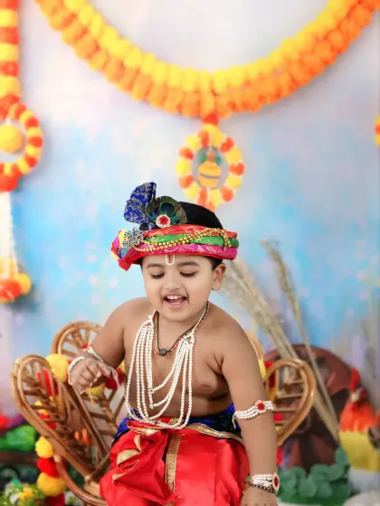 Pure joy is captured in this shot of a laughing toddler dressed as Krishna, seated on a wicker chair.