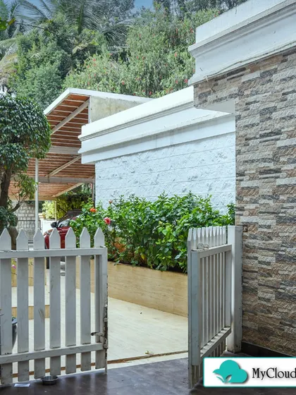 The entrance to this property is made more inviting with a white picket gate and lush plantings. The mix of stone textures on the wall and the greenery creates a rich and welcoming first impression.