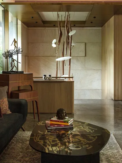 The entrance lobby of the Bammi Residence, where a sculptural light fixture by Klove Studio hangs above a staircase detailed with brass and wood. The space perfectly balances architectural drama with refined craftsmanship.