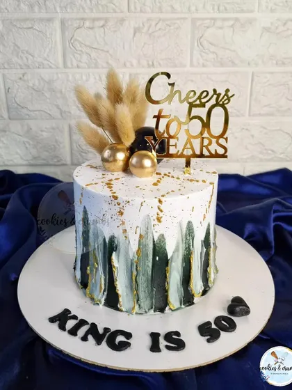 A popular design for milestone birthdays like 50th or 60th. This cake uses a palette knife technique with black, white, and gold, topped with dried botanicals for a rustic yet modern feel.