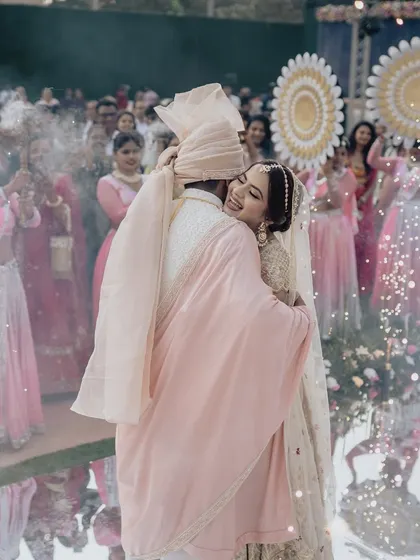 A hug that says everything. We design our Varmala stages, like this one with a mirrored aisle and cold pyros, to create an immersive and emotional atmosphere for the couple and their guests.