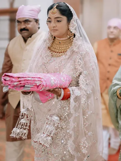 The bride during her Anand Karaj ceremony, looking elegant in her intricate white and silver lehenga. This shot captures her grace and the solemnity of the occasion.
