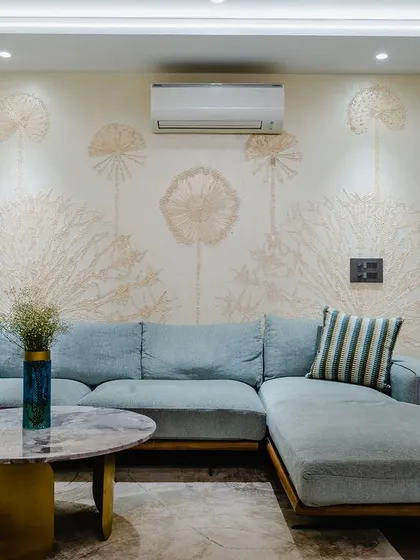 This cozy corner features a pastel blue low-slung couch set against a beautiful hand-painted mural. The nested marble and gold coffee tables add a touch of modern glamour.