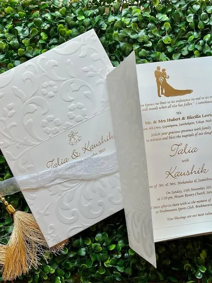 An elegant white embossed invitation for a Christian wedding. The gate-fold design opens to reveal the wedding details with a simple couple silhouette.