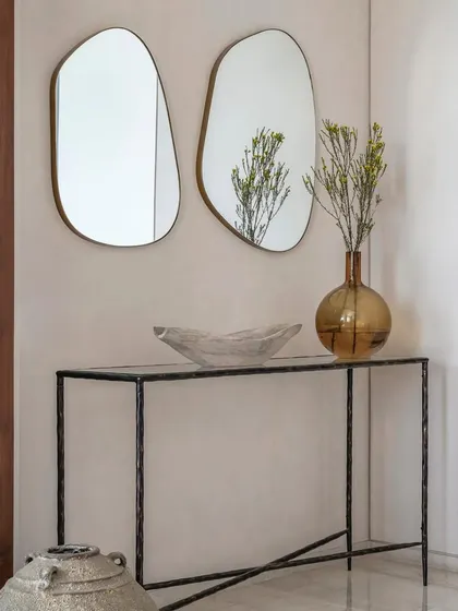 A detail of a console table in Apartment 1600, featuring organic-shaped mirrors and simple, elegant decor. This reflects the home's mid-century modern and coastal luxury theme.