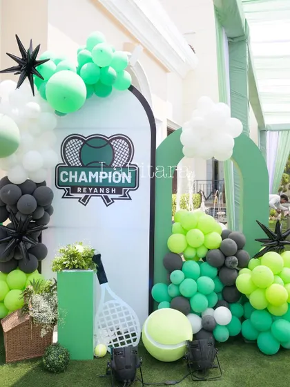 A stylish photo backdrop with a 'Champion Reyansh' logo, framed by a modern balloon garland.