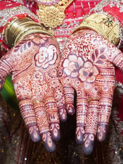A detailed shot of a bride's hands, showcasing the rich, dark color and intricate patterns of her bridal mehndi.