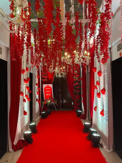 A truly dramatic and romantic entranceway. We lined the hall with red carpets and drapes, and created a ceiling of hanging red floral strings interspersed with elegant chandeliers.
