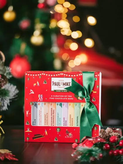 A Christmas-themed product shot featuring a festive chocolate gift box against a backdrop of twinkling lights. I use moody lighting and classic holiday colors to create a warm, inviting atmosphere for seasonal product photography.