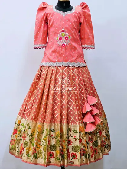 A lovely peach-colored lehenga with a floral border. The long-sleeved top has delicate embroidery, and the skirt features a combination of ikat and floral patterns.