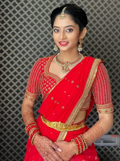 A happy portrait of Manya in her red ensemble. The hand-embroidered blouse features a classic sweetheart neckline and detailed work on the sleeves.