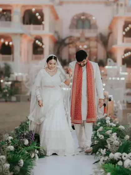 The couple's first steps together as husband and wife, walking down an aisle lined with flowers. This classic shot signifies the beginning of their new path.