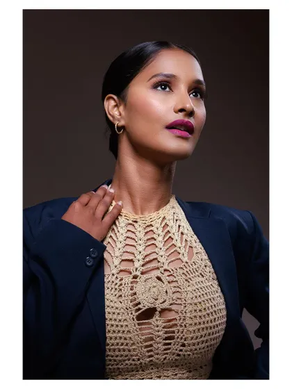 A sophisticated portrait featuring a crochet top and blazer. The lighting highlights the model's features and the texture of the clothing, creating a polished, high-fashion look.