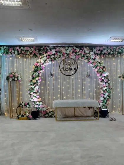 This is one of our most popular engagement and sakharpuda setups. The full floral arch, elegant white drapes with fairy lights, and a custom name hoop create a perfect, photo-ready backdrop for your special day.