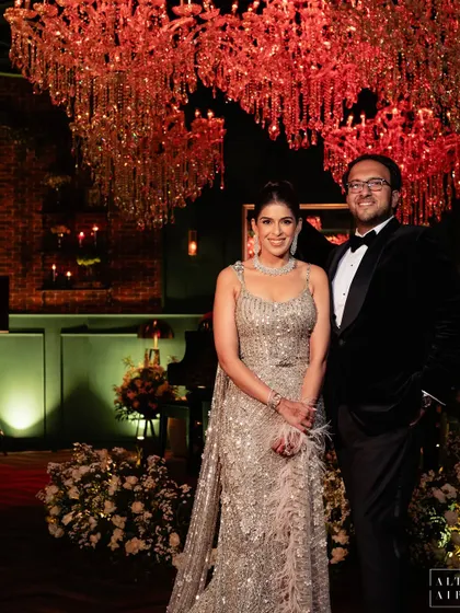 The couple at their contemporary reception, set in a glass house. The design blended old-world charm with mid-century modern elegance, creating a space brimming with history, culture, and warmth.