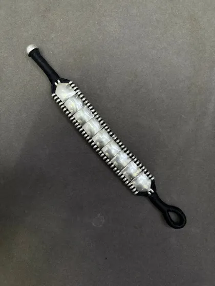 Another view of the woven silver bracelet on a black thread, showing the adjustable loop closure.