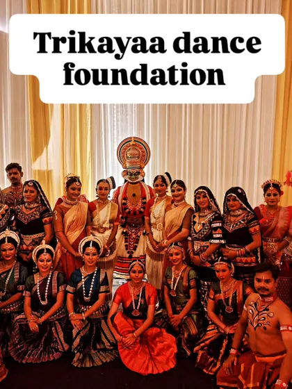A group photograph of the entire Trikayaa Dance Foundation troupe after a successful show. The central Kathakali artist is surrounded by dancers from various classical disciplines.