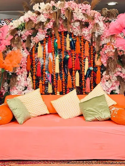 For this Mehendi, I went all-out with a bohemian and colourful theme. The backdrop features a dense arrangement of flowers, pampas grass, and vibrant tassels, creating a fun and high-energy setting perfect for the celebration.