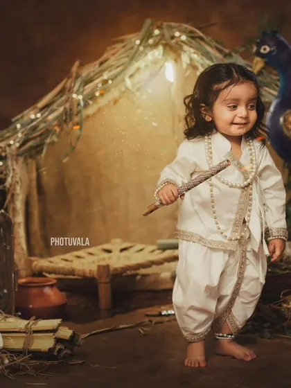 A confident little Krishna with his flute. The rustic hut and peacock in the background create a beautiful, traditional Vrindavan scene.