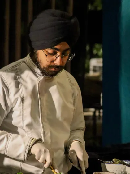 A chef concentrates on assembling a delicate dish. Our culinary team is composed of dedicated artists who bring focus and passion to their craft, ensuring perfection in every bite.