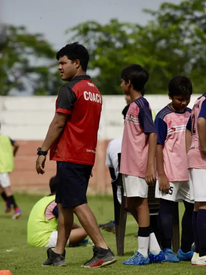 A coach observes the game from the sidelines during our Intra-Academy Football Championship, providing tactical guidance and support to the young players.