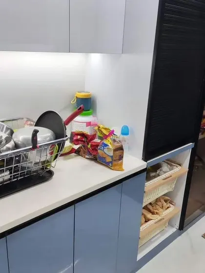 This angle shows the practical storage solutions we integrated, including wicker baskets for vegetable storage and a tall pantry unit with a rolling shutter. Every element is designed for easy access and a clutter-free experience.