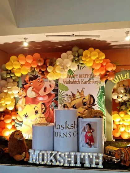 A fun and vibrant Simba theme for Mokshith's "Wild One" birthday. This setup includes a large backdrop with the characters, a "My First Year" photo board, and a warm-toned balloon garland.