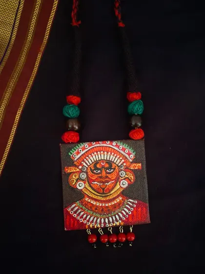 A slightly different version of the Theyyam pendant, with subtle variations in color and detail that make each piece unique.